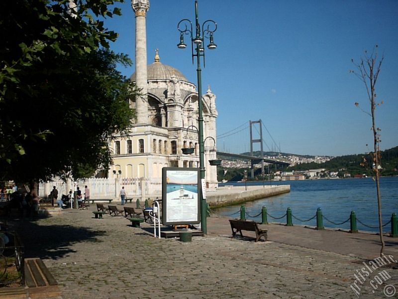 View of Bosphorus Bridge, Ortakoy Mosque and the moon seen in daytime over the bridge`s legs from Ortakoy shore in Istanbul city of Turkey.
